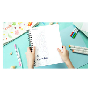 Artist using an Ohuhu marker pad at a desk with art markers